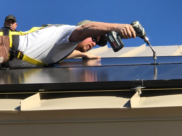 contractor installing a rail-less solar PV mounting system using a screw gun