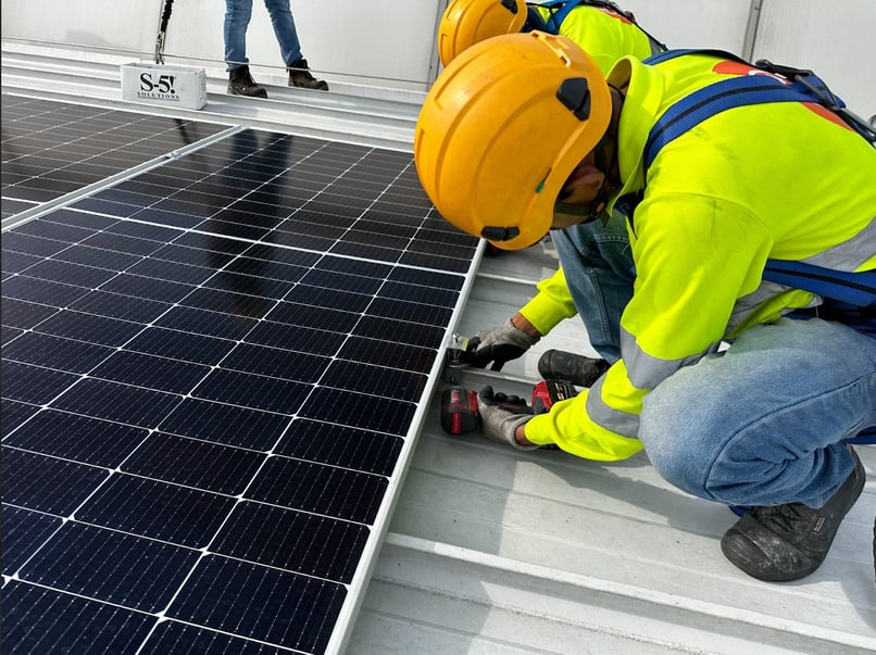 Installer securing a solar panel on a metal roof using a UL 3741-compliant mounting system.