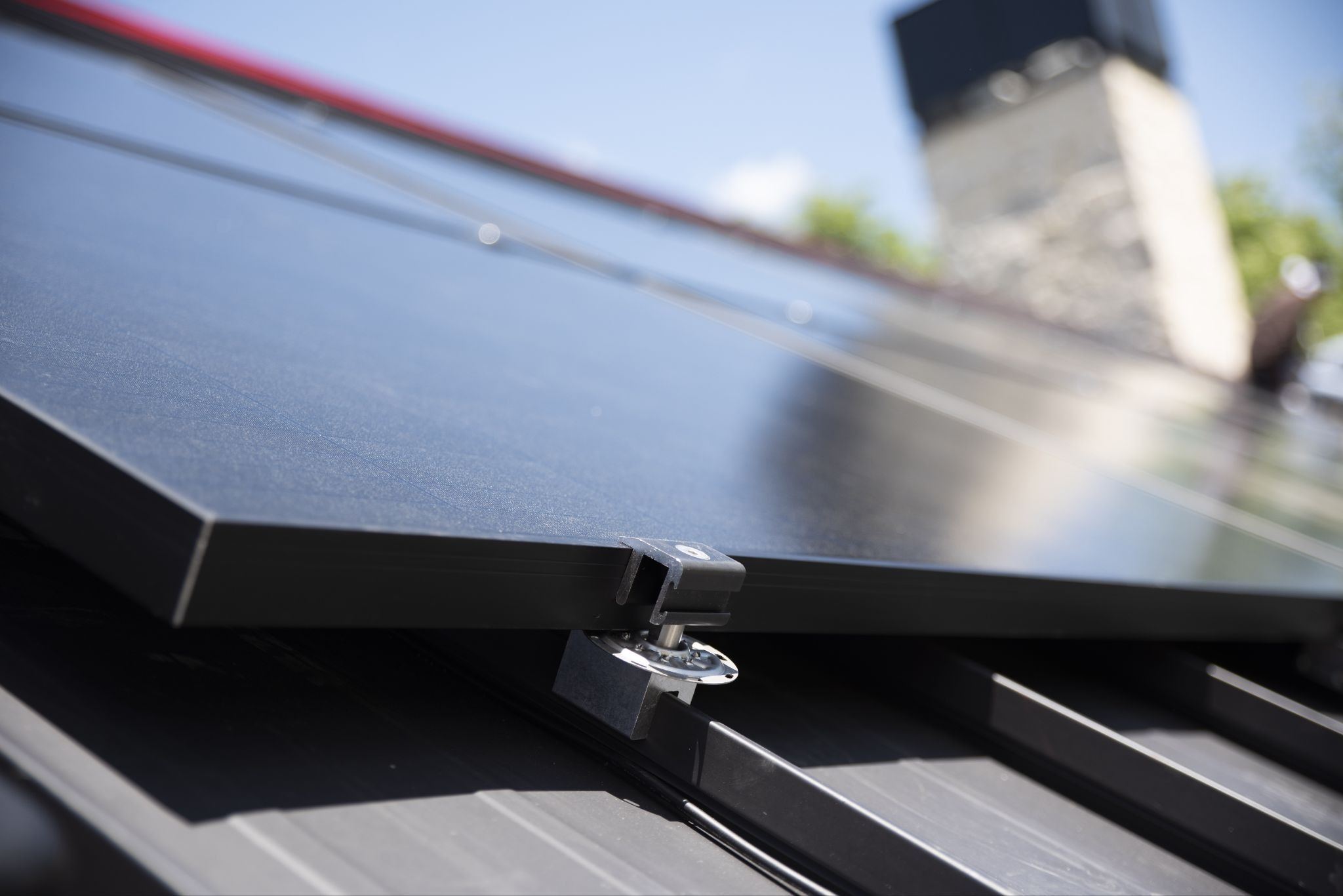 Abrazadera sin perforación que fija paneles solares a un techo metálico engargolado.